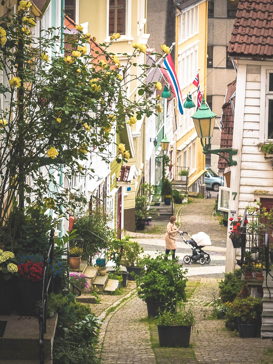 woman walking with stroller on picturesque cobbled street in bergen norway