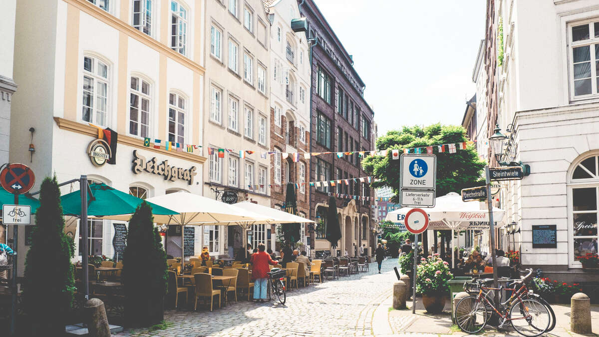 cobbled street in hamburg germany with restaurants and cafes serving food outside a sunny day