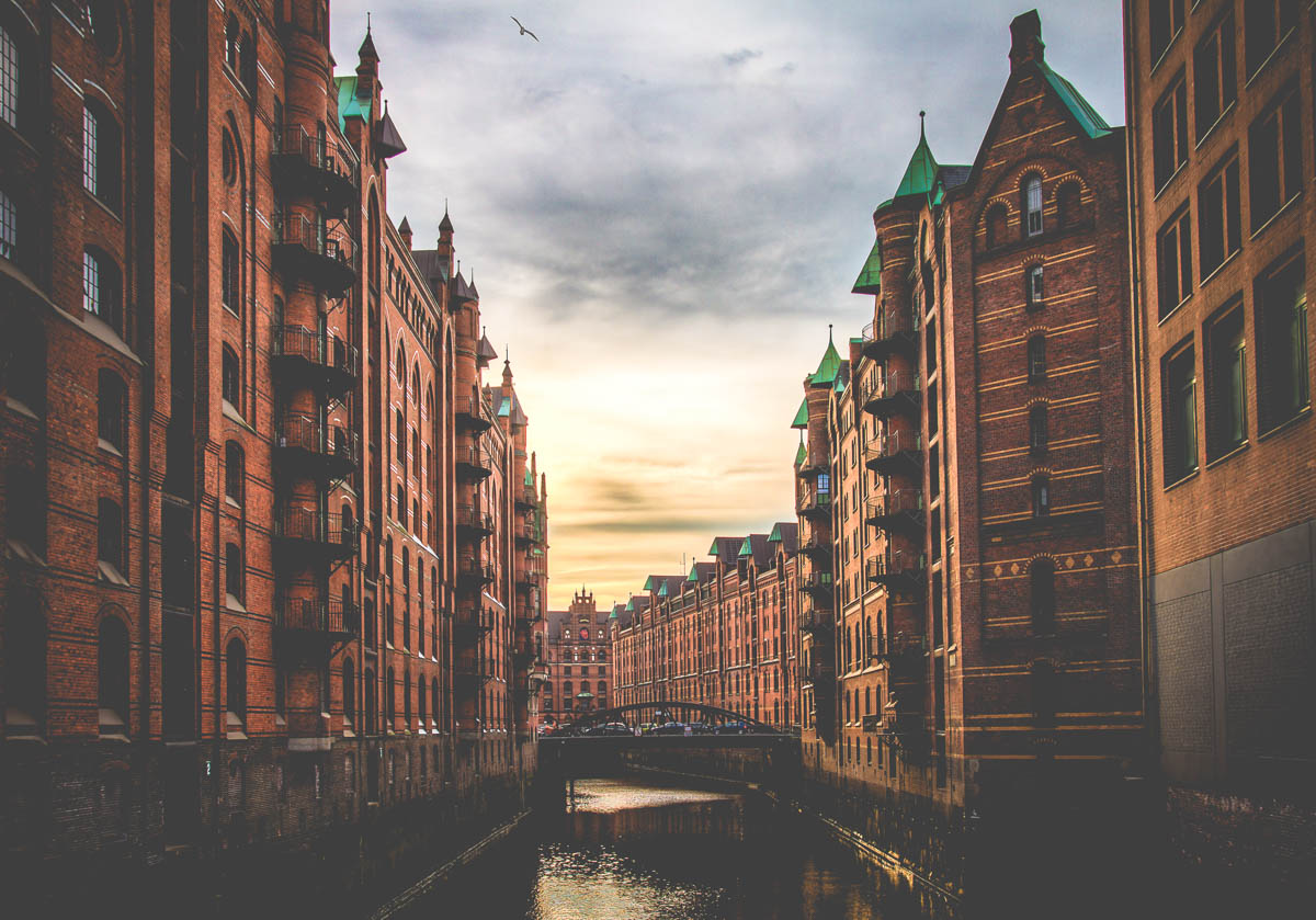 speicherstadt warehouse district in hamburg with red brick buildings on poles in water with bridges crossing the water kanals